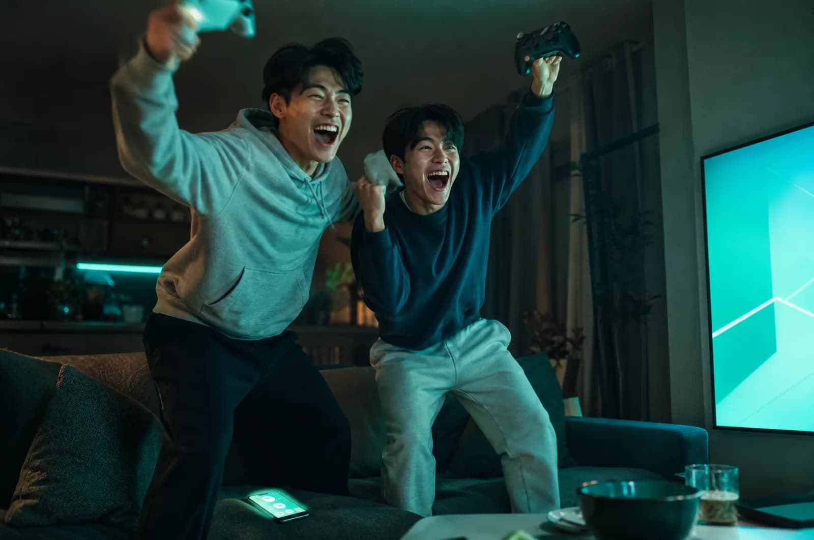 ゲームに勝った瞬間、ソファから立ち上がって喜ぶ2人の友人